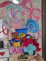 Ancheta de cumpleaños artesanal con flores tejidas en chenille, dulces De Todito y globo burbuja decorada en tienda Valeland Barbosa