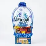 Ancheta para hombre tipo globo aerostático con globo burbuja Feliz Cumpleaños, gomitas Grissly, galletas y caja Disfruta Tu Día sobre fondo blanco